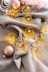 leuchtende Lichterkette auf einer grauen Decke mit goldenen Ornamenten