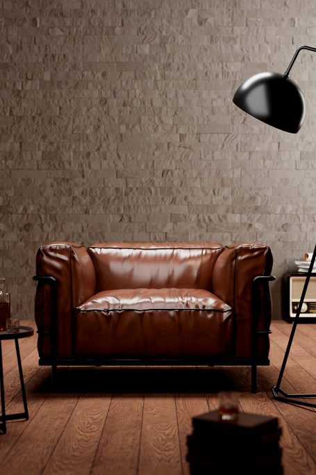 CGI-Aufnahme, 3D-Design, braunes Ledersofa vor einer grauen Wand, neben einer Stehlampe und einem kleinen Tisch.