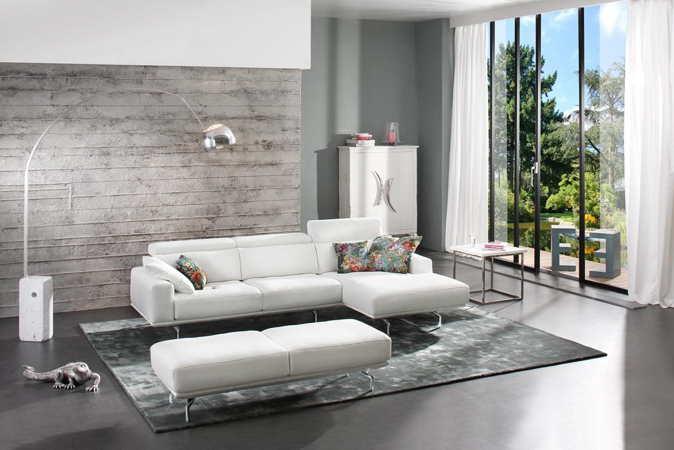 Helle, moderne Wohnlandschaft mit weißem Sofa, Teppich und großen Fenstern.